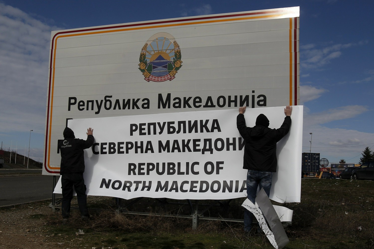 Radnici prelepljuju tablu nalepnicom na kojoj piše „Republika Severna Makedonija“ na južnoj granici sa Grčkom u blizini Đevđelije, 13. februar 2019. (Foto: AP Photo/Boris Grdanoski)
